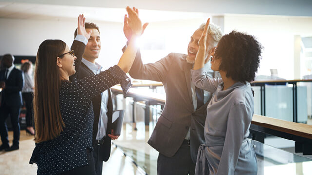 Happy professional people doing hi five in the office.